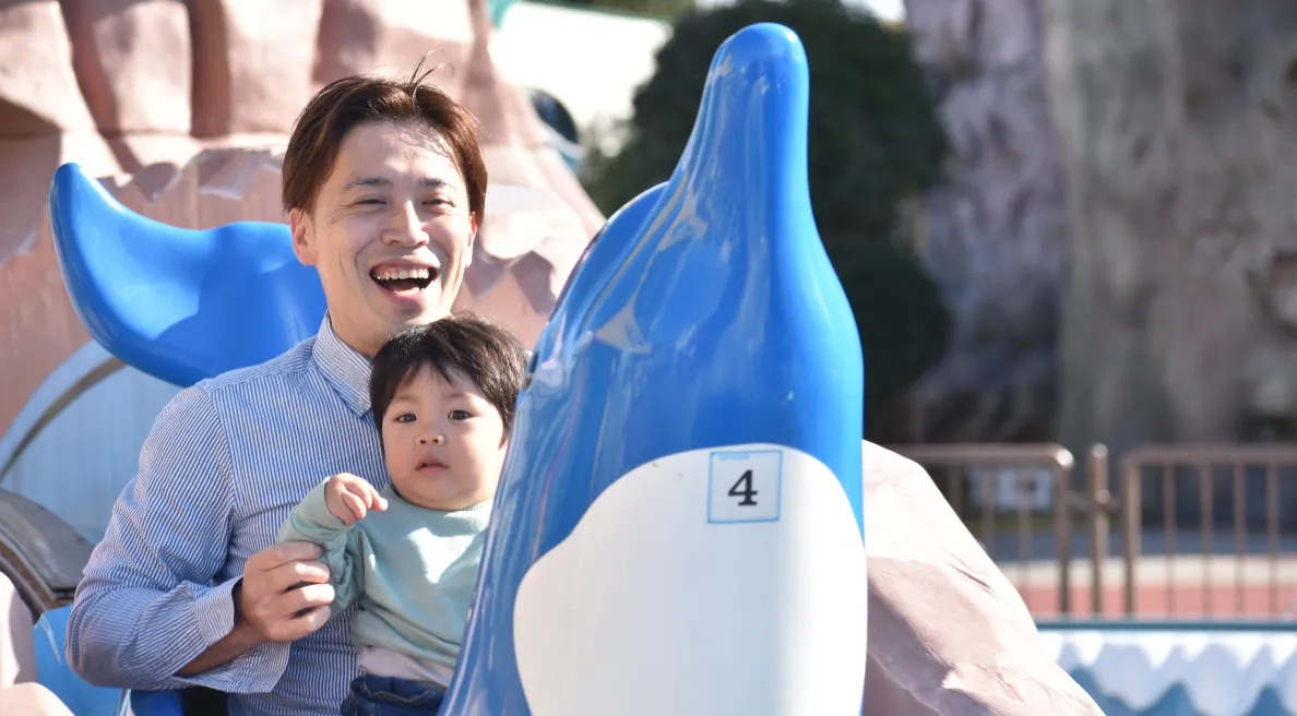 写真：イルカの乗り物に乗っているお父さんと小さい男のお子さん
